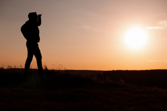 Silhouetted Man Shielding Eyes Against the Sunset Sky