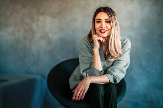 A relaxed caucasian woman smiling in a soft, modern interior, creating a warm lifestyle portrait