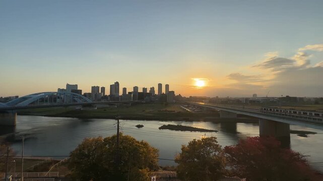 Warm sunset reflecting on the Tama River with a view of the Kawasaki city skyline and bridges