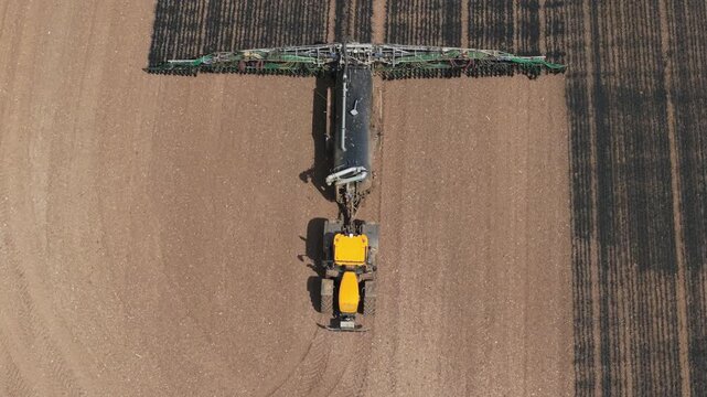 Liquid manure fertilizer application by tractor in agricultural field. Precision farming machinery improving soil fertility, crop productivity, sustainable agribusiness efficiency. Farm equipment
