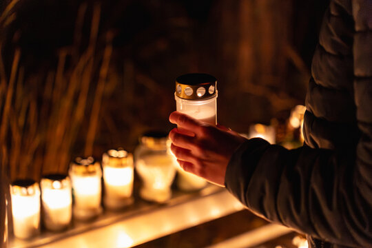 person holding lit memorial candle outdoors at night during All Saints Day in Stockholm
