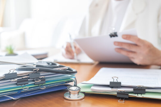 Healthcare personnel managing medical records, documents, and patient files, with a stethoscope on a desk, representing data organization and administrative tasks in medicine