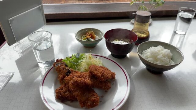 Dolly out from a delicious japanese katsu set meal with rice, soup, and pickles in a restaurant