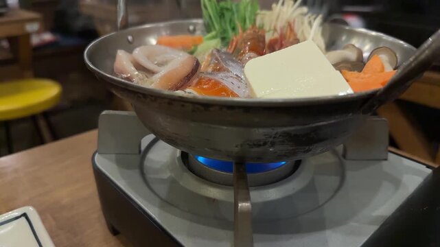Traditional Japanese seafood hot pot, nabe, boiling with fresh ingredients in a restaurant