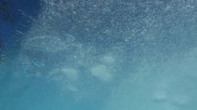 Thin thawing spring clear ice with frozen air bubbles drifting downstream along the shore on a blue sky background, underwater view, close-up, natural background 