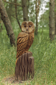 Beautiful wooden owl sculpture carved from tree trunk in forest