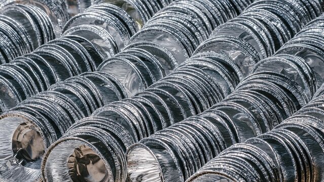Stack of empty aluminum food containers arranged in neat rows. Industrial manufacturing and supply of metal packaging for food storage. Sustainability and metal recycling industry concept.