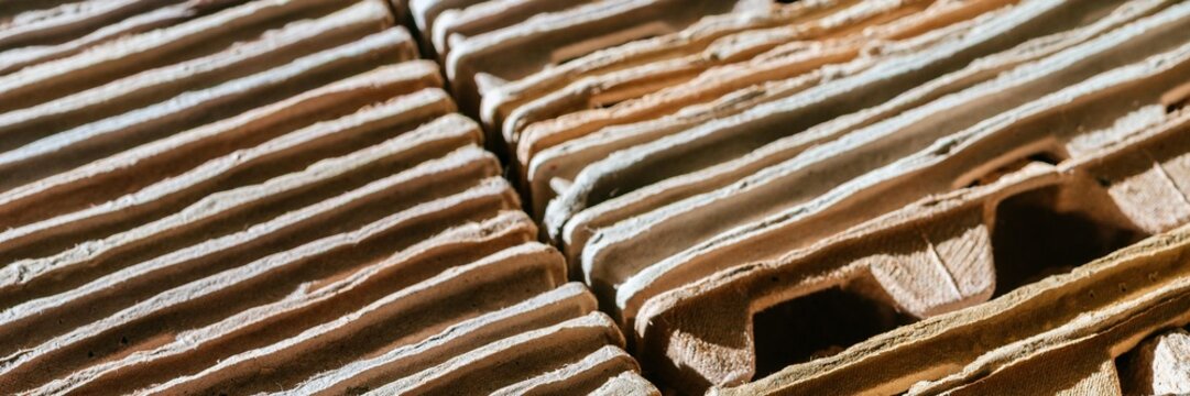 Stack of recycled cardboard sheets arranged for industrial processing. Concept of waste sorting and sustainable packaging material. Environmental conservation and industrial recycling.