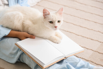 Obraz premium Little boy with cat and book sitting in bedroom, closeup