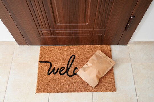 Paper bag on mat near door in hallway, top view. Delivery service