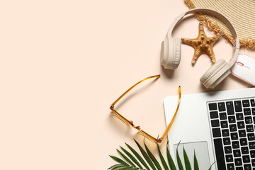 Obraz premium Laptop with headphones, mouse and beach accessories on beige background