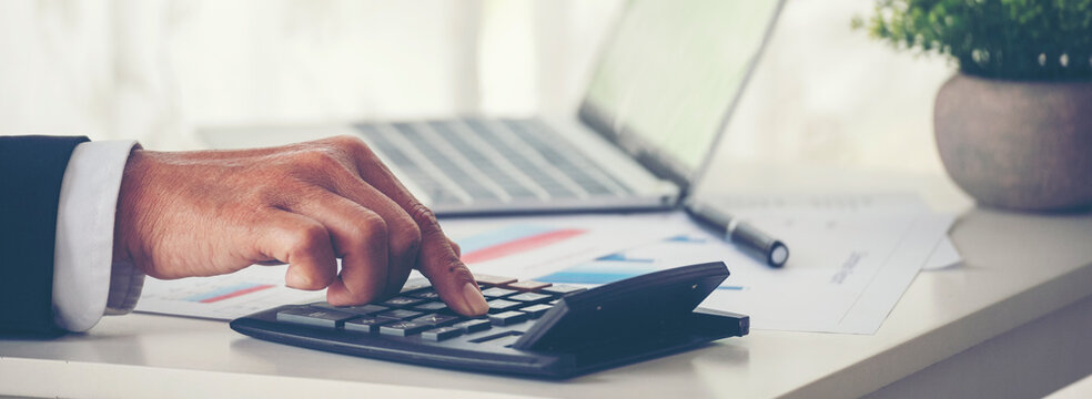 Banner Asian Business man hands using calculator counting tax financial bill. Business Graphs charts on office desk with copy space. Banner Excel graph with Spreadsheet Document showing Information