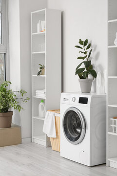 Modern washing machine with basket and shelving units near white wall. Interior of home laundry room