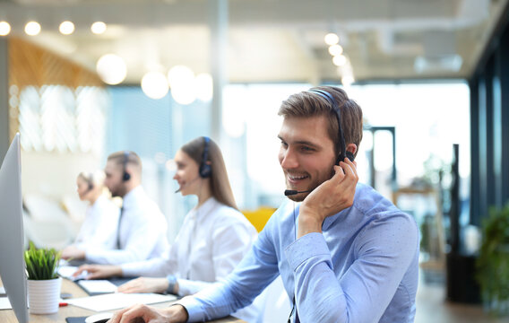 Portrait of call center worker accompanied by his team. Smiling customer support operator at work.
