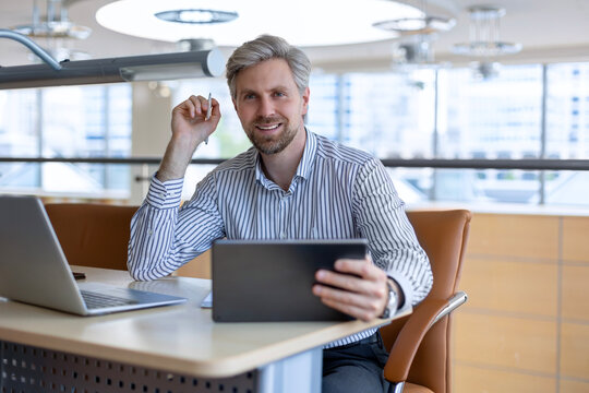 Young modern business man working using digital tablet while sitting in the office