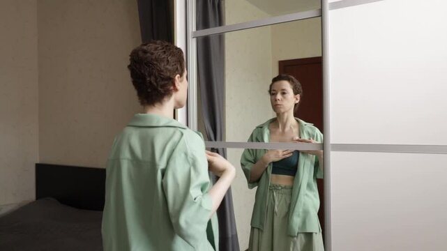 woman faces her reflection with one hand over the implanted port, expressing body awareness, emotional resilience and daily self care during cancer recovery at home
