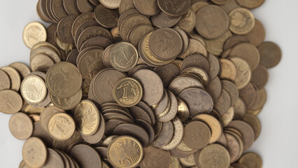 A pile of Polish grosz coins scattered on a white surface, with various denominations visible, including 1 grosz and 2 grosz coins. © Piotr Adamczyk