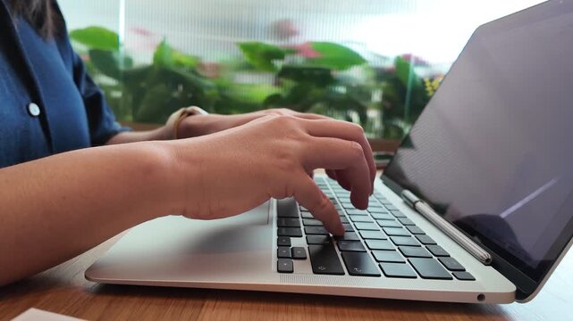A businesswoman typing on a laptop while reviewing financial documents at a modern office desk, creating a productive and professional working environment.