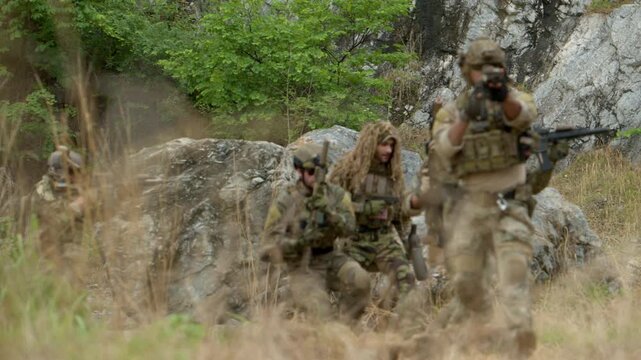 Special operations soldiers react to a controlled explosion during a tactical military training exercise in rugged outdoor terrain