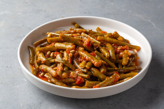 Traditional Turkish green beans stew cooked with tomatoes and olive oil on a ceramic plate