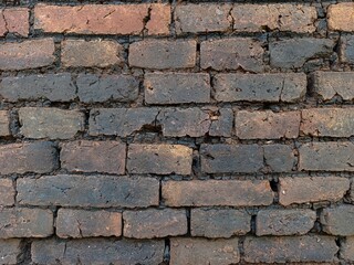 Obraz premium Close-up of an old weathered brick wall with cracked clay bricks and rustic masonry texture, ideal as an authentic architectural background or construction design element.