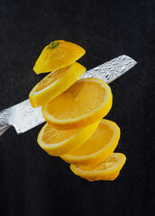 Levitation of freshly cut lemons. A knife cuts a lemon in the air. Flying slices of lemon isolated on a black background. Drops of water on black. © Marina Dubin