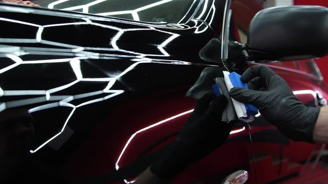 4K video of ceramic coating application. Liquid glass sealant on black automotive paint. Vehicle detailing process for scratch resistance and aesthetic preservation