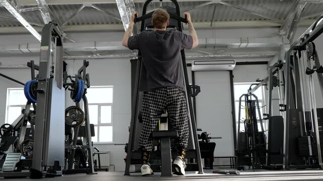 Male athlete performing seated lat pulldown in modern gym, pulling overhead cable bar downward with controlled form during focused back strength workout