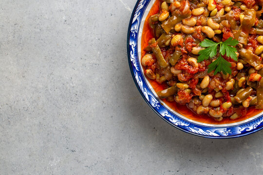 Traditional Turkish fresh black-eyed pea stew with tomatoes and olive oil served in a blue patterned bowl.