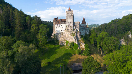 Naklejka premium Aerial view of the famous medieval Bran Castle surrounded by green forest in Transylvania, Romania.