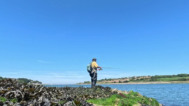 Un p&ecirc;cheur &agrave; la canne &agrave; lancer sur le bord d'une rivi&egrave;re en Bretagne