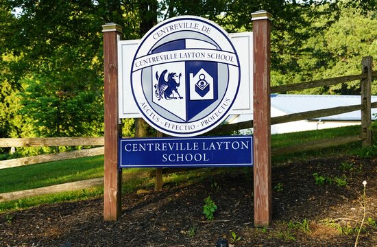 New Castle County, Delaware, U.S.A - Jul 2, 2026 - Centreville Layton School sign featuring crest, motto, and wooden posts set among grass and trees.