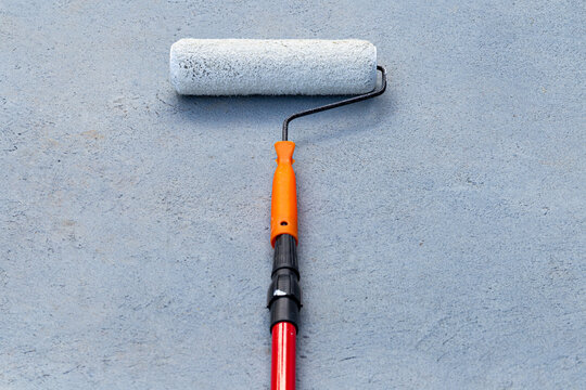 Paint roller on a blue gray textured wall background