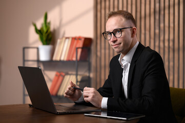 Fototapeta premium Confident Business Consultant Looking at Camera While Working at Laptop in Modern Office