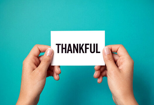 Grateful person holding a white card with thankful message in bold letters