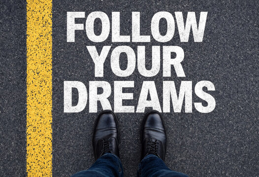 Motivational message painted on asphalt with feet standing near yellow line ready to inspire