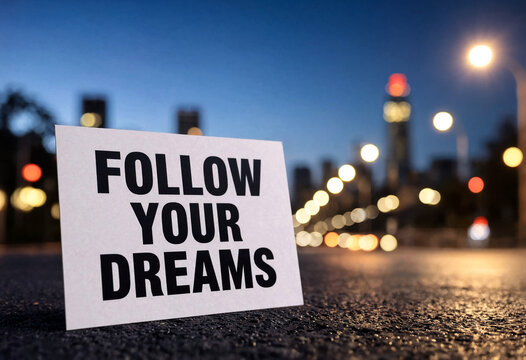 Motivational sign with follow your dreams message on a city street during evening time