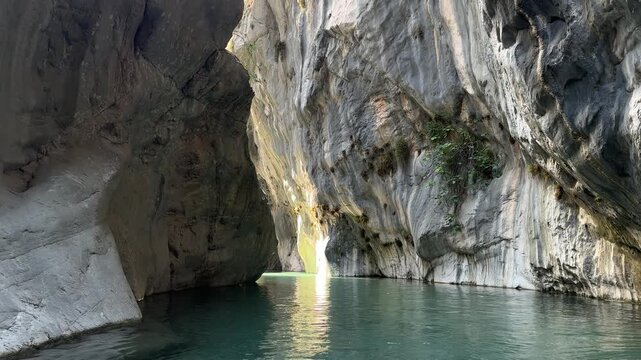 Scenic view of a narrow canyon with steep rock walls and lush greenery reflected in the calm water, showcasing the natural beauty of the landscape in a serene environment