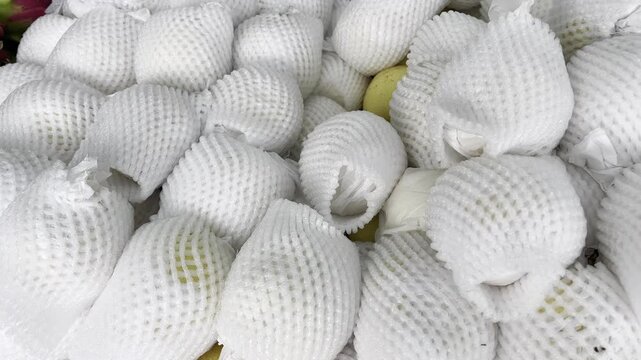 Fresh white pears packed in protective foam nets at market
