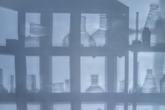 Abstract background with shadows of laboratory equipment and glassware projected on a surface, blue cinematic lighting, science backdrop with copy space.