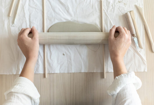 Women artist pottery shaping clay on a worktable with tools and cloth