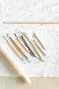 Creative clay pot on worktable with wooden handles and cloth, top-down