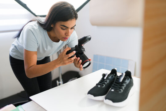 Female photographer capturing product images of black sneakers in a studio with professional lighting setup