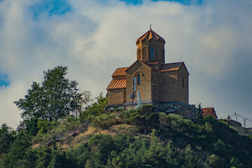 Fototapeta premium Ancient Narikala fortress church on hill in Tbilisi with dramatic sky copy space