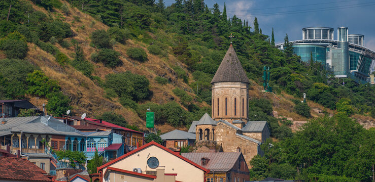 Architectural contrast in old Tbilisi with ancient church and modern glass mansion