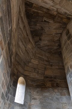 Interior of a round stone tower, corner where masonry walls curve inward to support the ceiling.