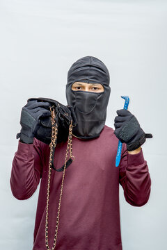 Masked thief holding stolen gold chain. Criminal with crowbar committing robbery. Dangerous burglar.