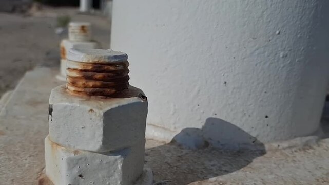 Macro close-up of weathered rusted bolts and industrial metal hardware on a concrete structure, industrial detail shot.