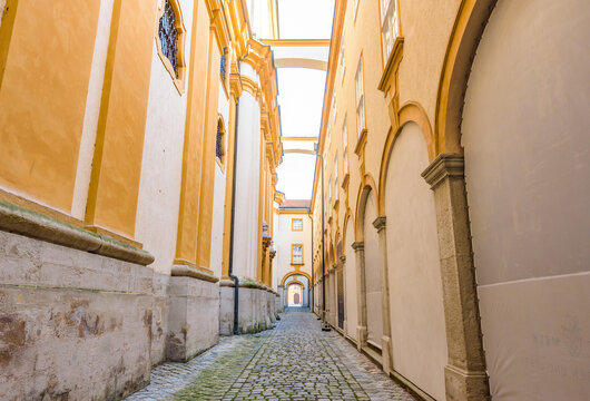 A scenic cobblestone alley between historic baroque buildings inside Melk Abbey, a UNESCO World Heritage Site of the Wachau Cultural Landscape, Austria