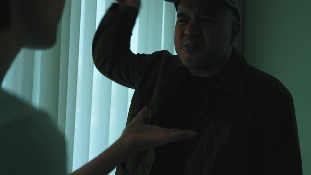 Asian man and woman aggressively arguing in a dark room. Concept of domestic conflict, toxic relationship, marriage problems, unhappiness and emotional abuse.